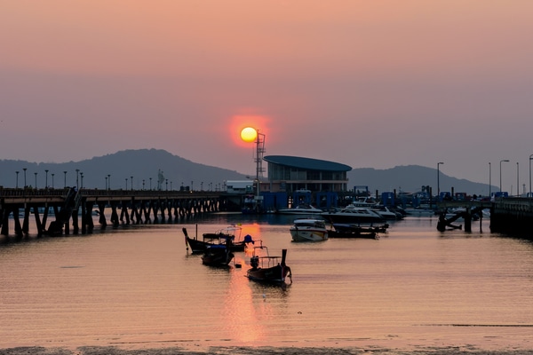 Chalong Pier at sunrise with boats anchored along the jetty