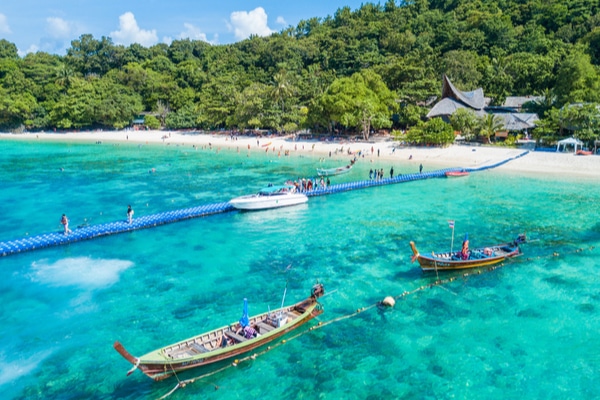 longboats docked at banana beacj next to the pier set against a lush backdrop