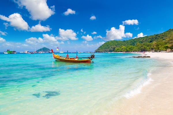 a longboat sits waiting for use in the crystal clear waters off the shore at long beach