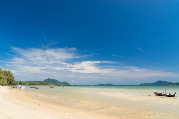 rawai beach as seen from the beach looking out towards some long tail boats floating in the open waters