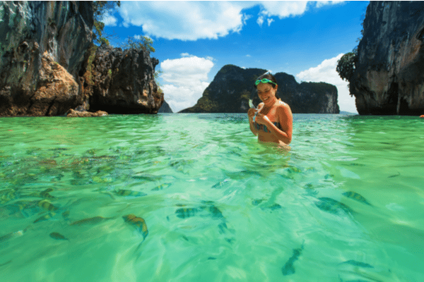 A woman snorkeling amongst a wide array of colourful fish at phi phi leh
