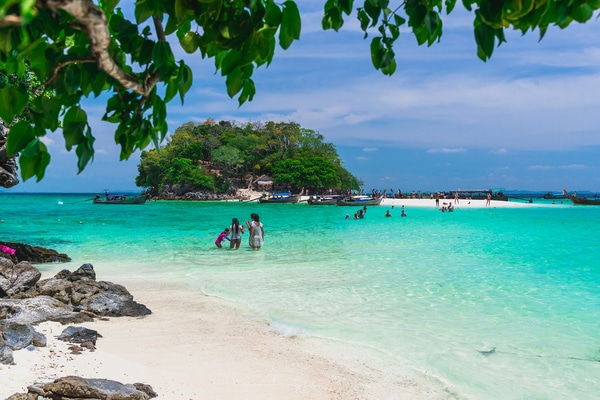 Tup Island as seen from the beach with swimmers in the crystal clear waters just off the shore
